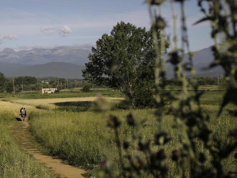 Zwei Flüchtlinge verlassen das ehemalige Flüchtlingscamp Idomeni in Griechenland. Dieses wurde im Mai 2016 geräumt.