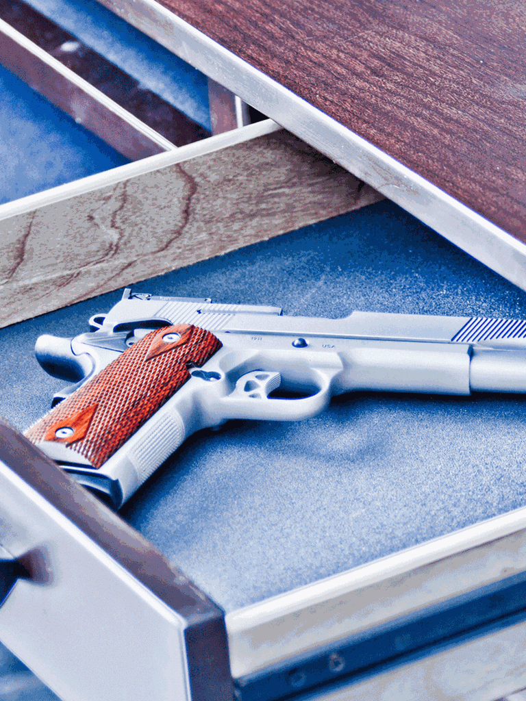 Gefährliche Neueinstellung: Als Reinigungskraft hat Iris Zugang zu fast allen Schubladen im Rathaus. Eine geöffnete Schublade mit einer Pistole darin.