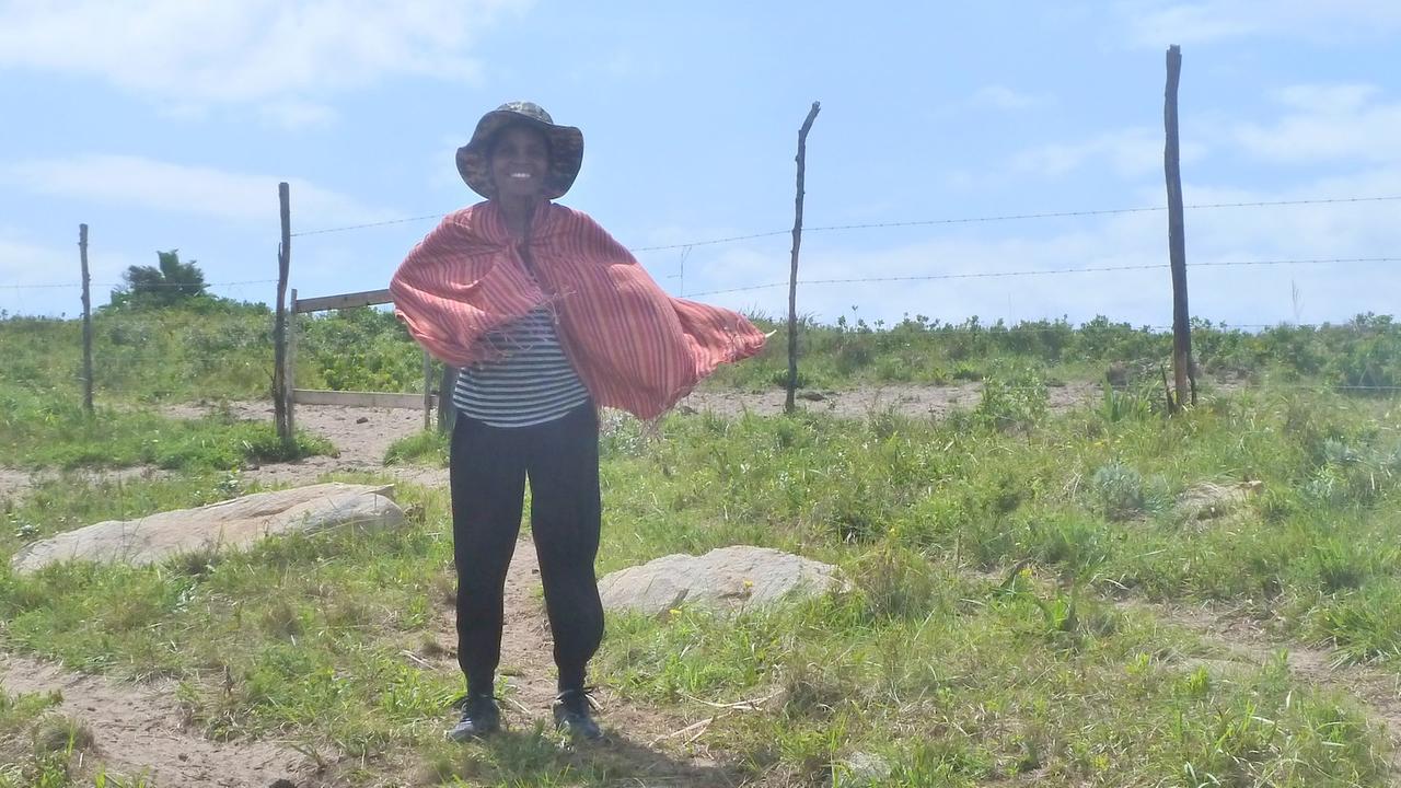 Pondoland-Aktivistin Nonhle Mbuthuma steht mit wehendem Schal vor einem Holzzaun