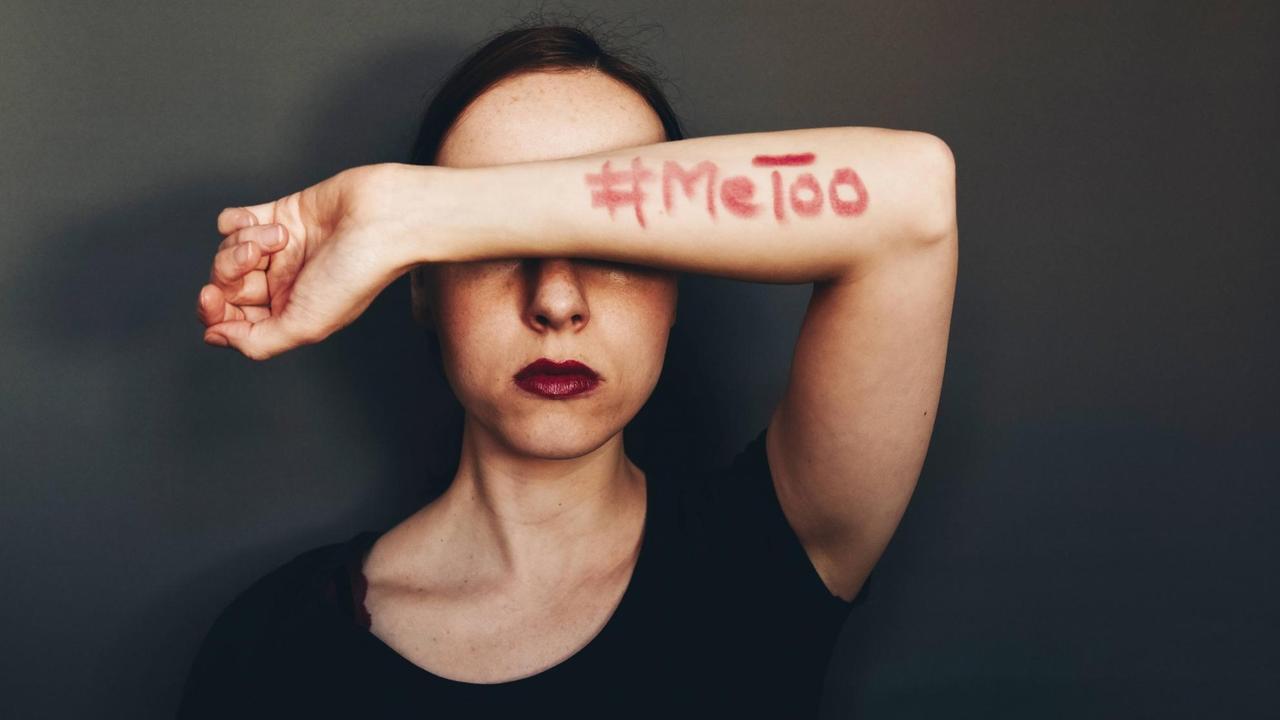 Eine Frau hält sich einen Arm vor das Gesicht, auf dem mit roter Farbe geschrieben steht: MeToo Eine Frau hält sich einen Arm vor das Gesicht, auf dem mit roter Farbe geschrieben steht: MeToo