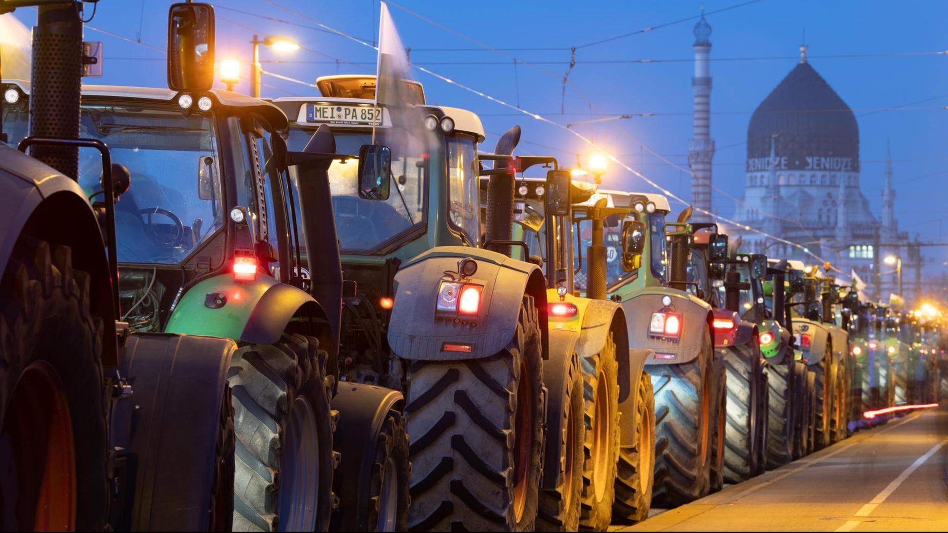 17.01.2020, Sachsen, Dresden: Traktoren stehen im Morgengrauen auf der Marienbrücke hintereinander.
