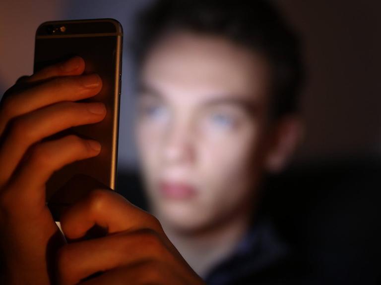 Ein Jugendlicher schaut auf sein Smartphone