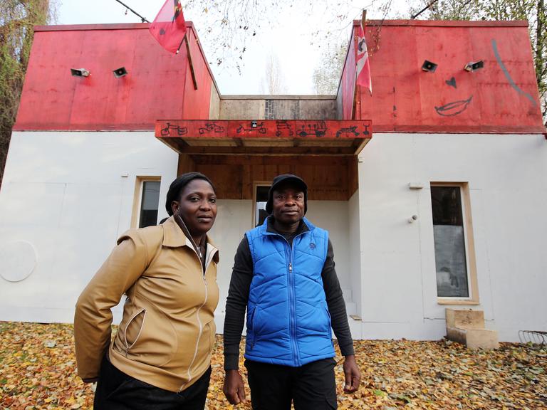 Der Sprecher der Lampedusa-Gruppe, Asuquo Udo, und Esther Olaide Olokodena, Mitglied der Gruppe, vor dem Kunstprojekt und Flüchtlingsquartier "Ecofavela" auf Kampnagel in Hamburg.