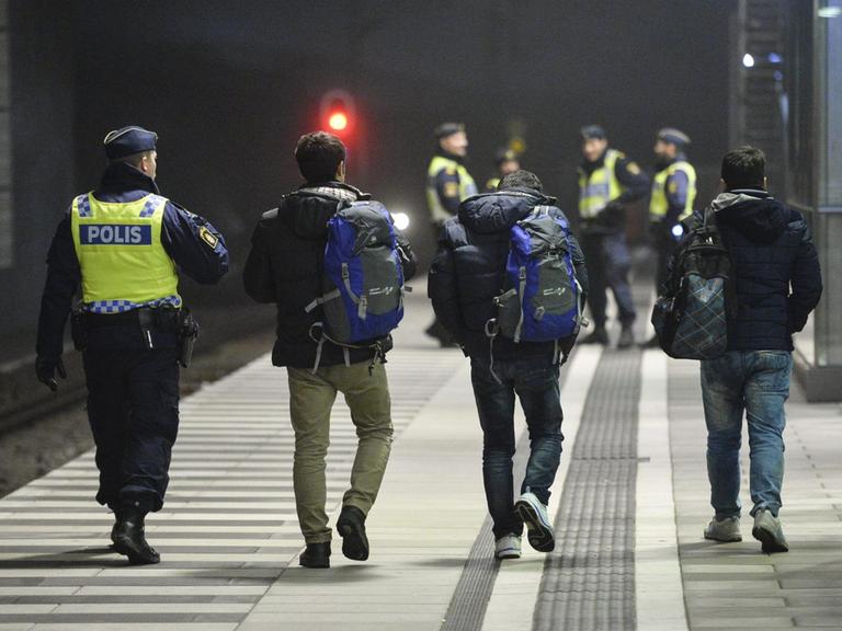 Ein schwedischer Polizist mit Flüchtlingen am Bahnhof Hyllie in der Nähe von Malmoe.