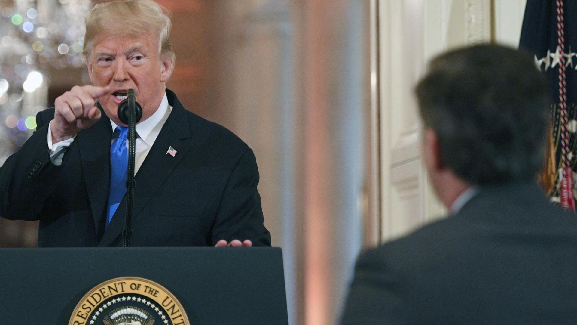 US-Präsident Trump steht hinter einem Mikrofon im Weißen Haus und zeigt mit dem Zeigefinger auf den CNN-Journalisten Jim Acosta, der zuvor eine Frage gestellt hatte.