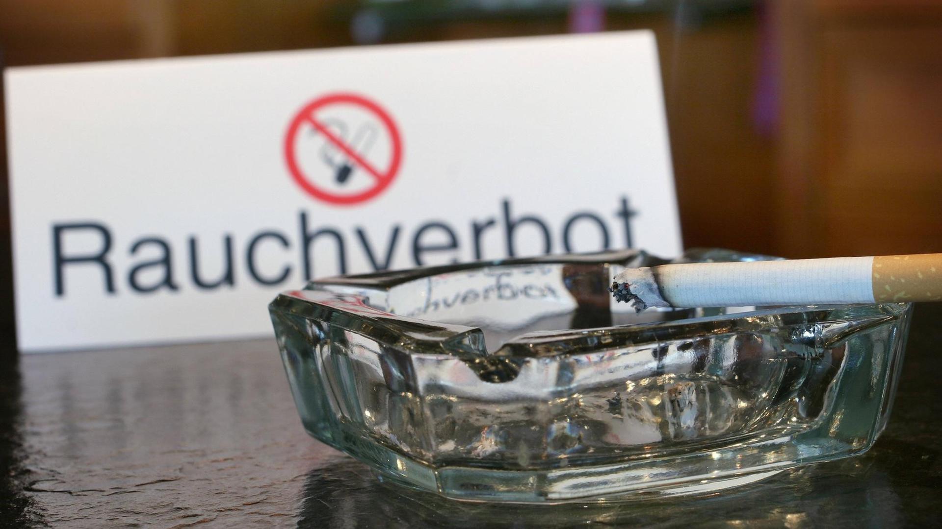 Ein Aschenbecher und ein Nichtraucherschild. Seit zehn Jahren gilt das bundesweite Rauchverbot in Gaststätten