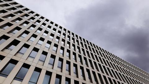 Schräg von unten erhebt sich das Gebäude des BND gegen einen dramatisch bewölkten Himmel.