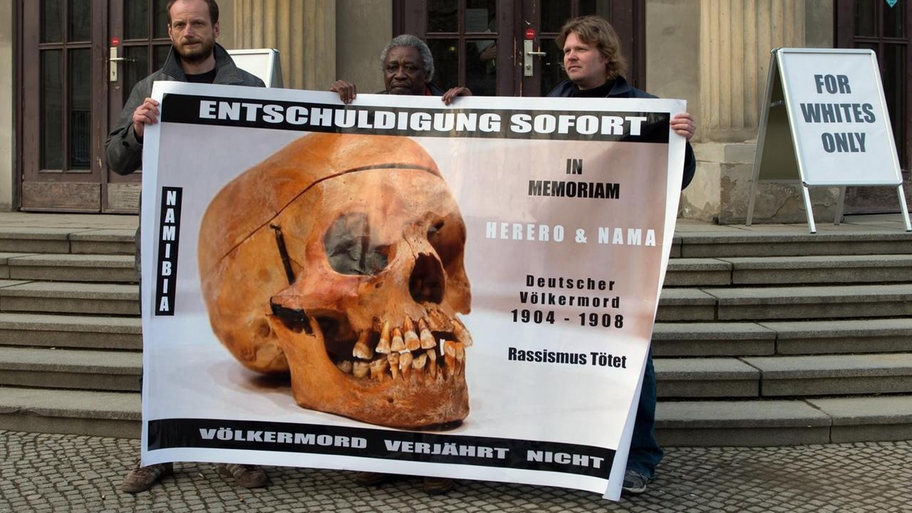 Demonstranten mit einem Transparent "Entschuldigung sofort - Völkermord verjährt nicht" vor einem Gebäude der Charite in Berlin