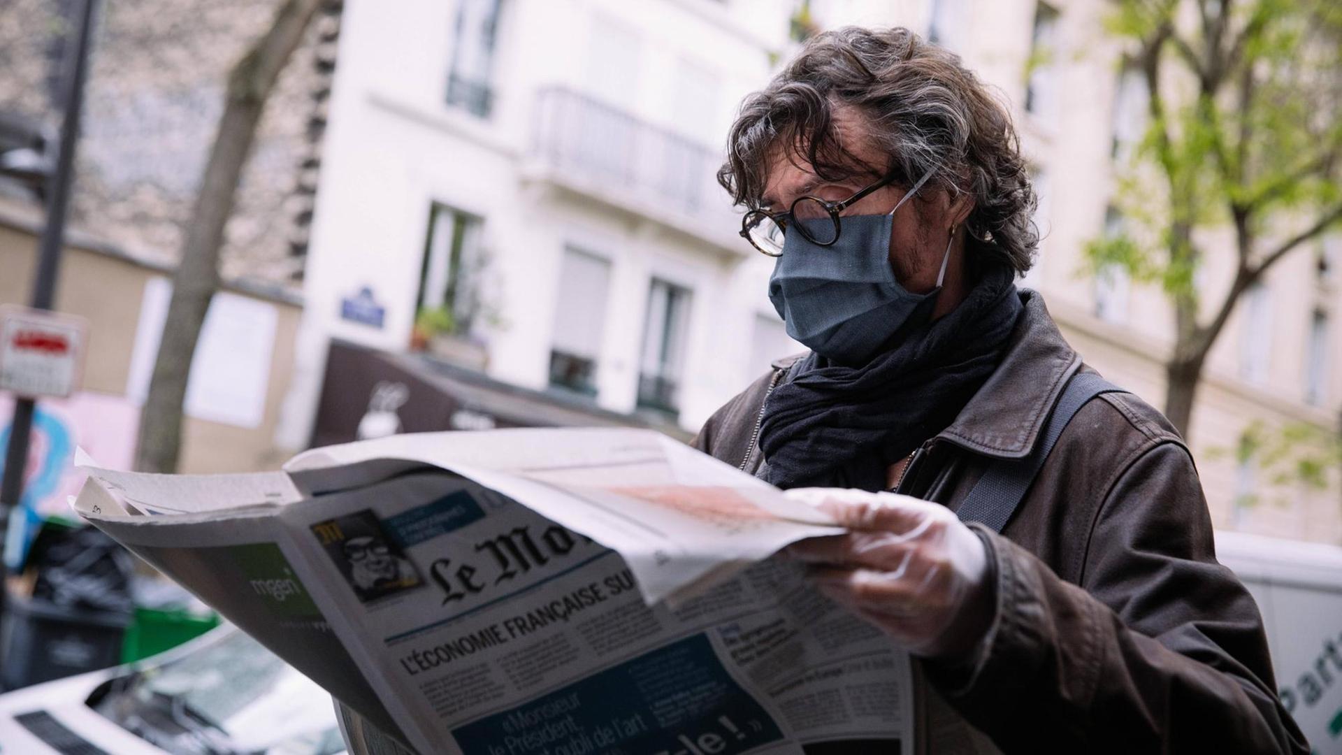 Ein Mann mir Mundschutz liest die Zeitung "Le Monde" in Paris.