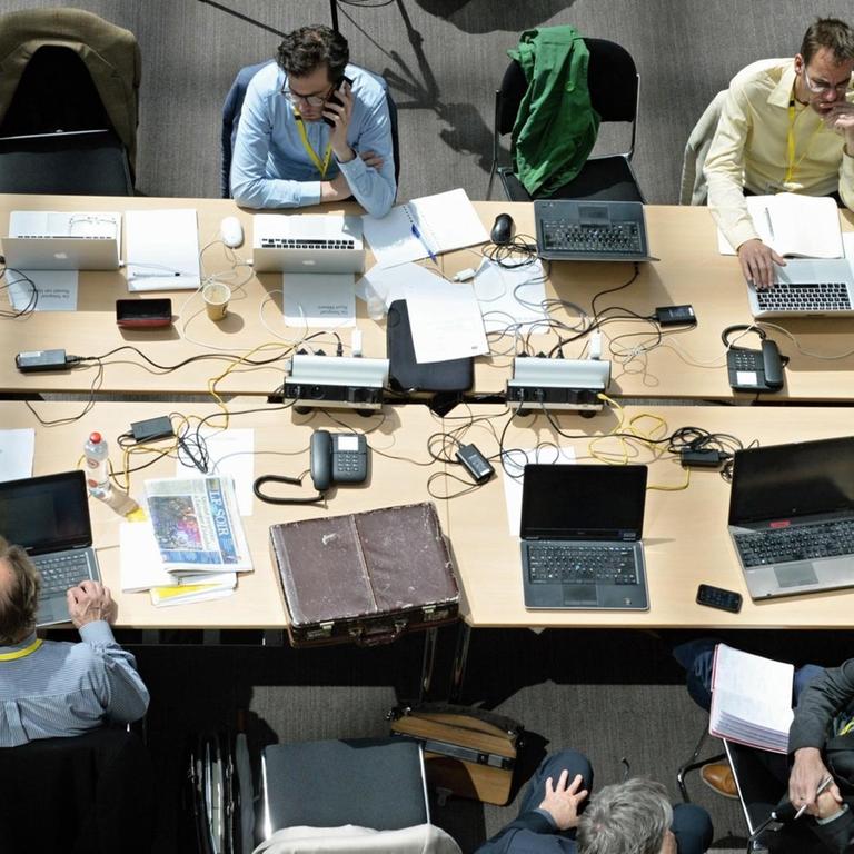 Journalisten sitzen mit Laptops an einem Tisch im Pressezentrum im Foyer des Justus-Lipsius-Gebäude in Brüssel