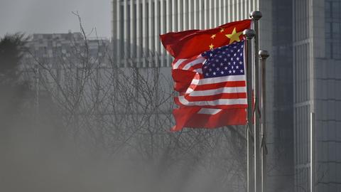 Eine US-amerikanische und eine chinesische Flagge wehen im Wind. Sie sind vor einem Bürogebäude in Chinas Hauptstadt Peking angebracht.