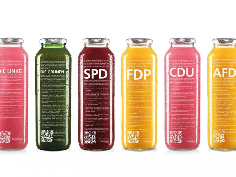 Sechs Glasflaschen mit verschieden farbigen Smoothies. Beschriftet sind sie mit „Die Linken“, „Die Grünen“, SPD, FDP, CDU und AFD.