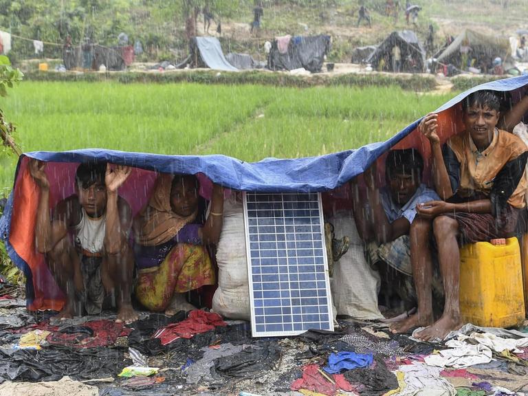 Angehörige der Rohingya schützen sich in einem Flüchtlingslager in Bangladesch vor Monsun-Regen.