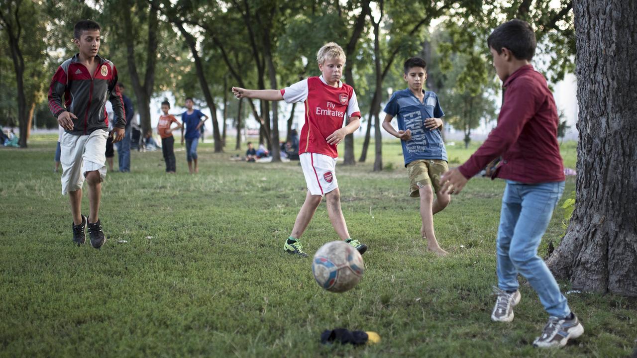 Kinder unterschiedlicher Herkunft spielen Fußball zusammen.