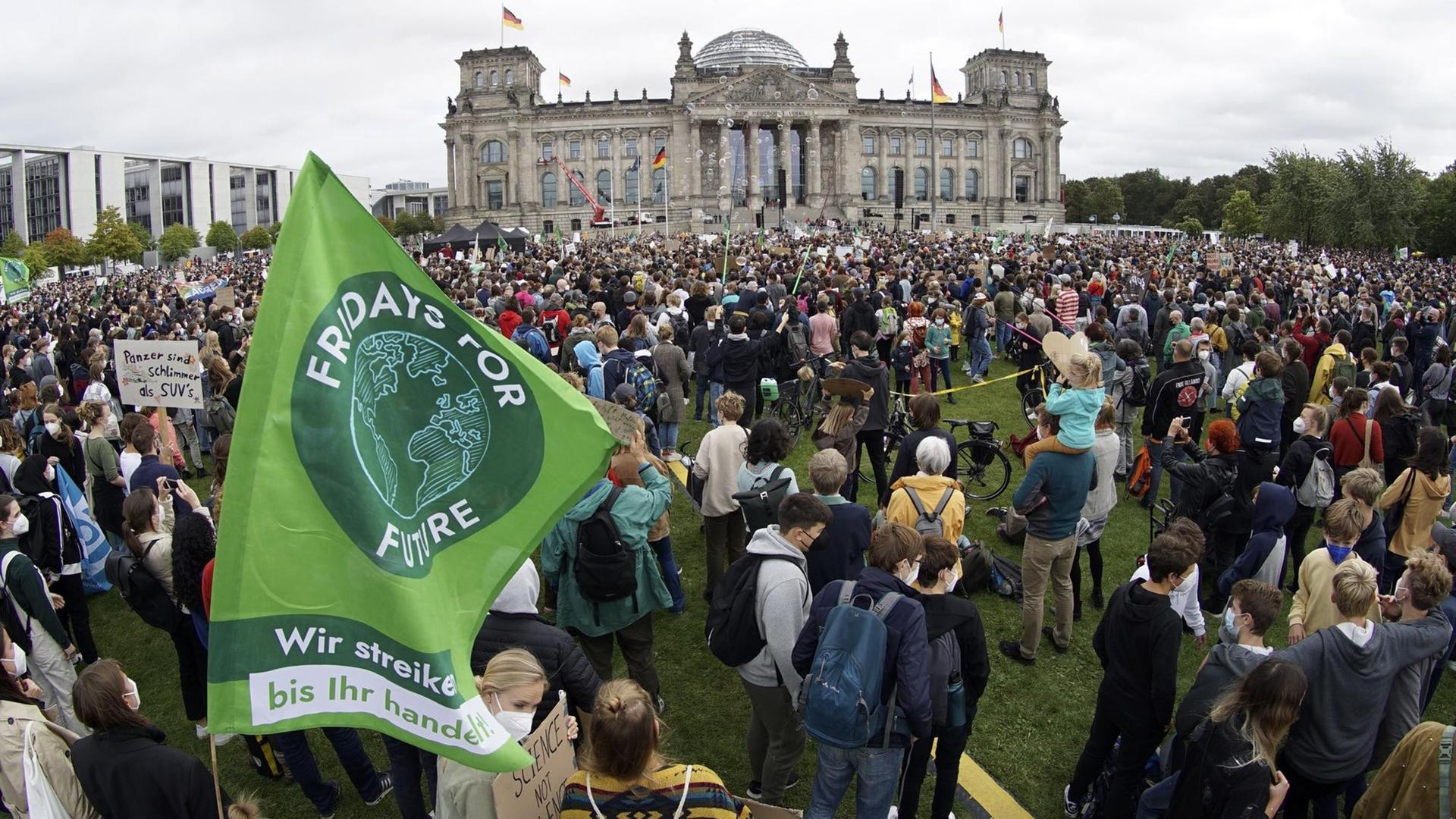 Demonstrantinnen und Demonstranten stehen vor dem Bundestag. Auf einer Fahne steht Fridays for Future.