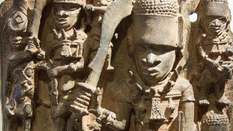 Benin Bronzen - Skulpturen aus dem Königreich Benin hinter einer Vitrine bei einer Ausstellung.