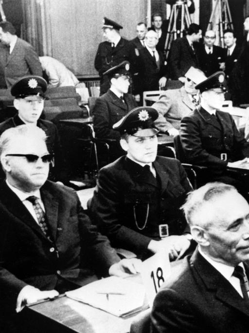 22 ehemalige Wachen und Beamte des Konzentrationslager Ausschwitz stehen im Dezember 1963 in Frankfurt vor Gericht.