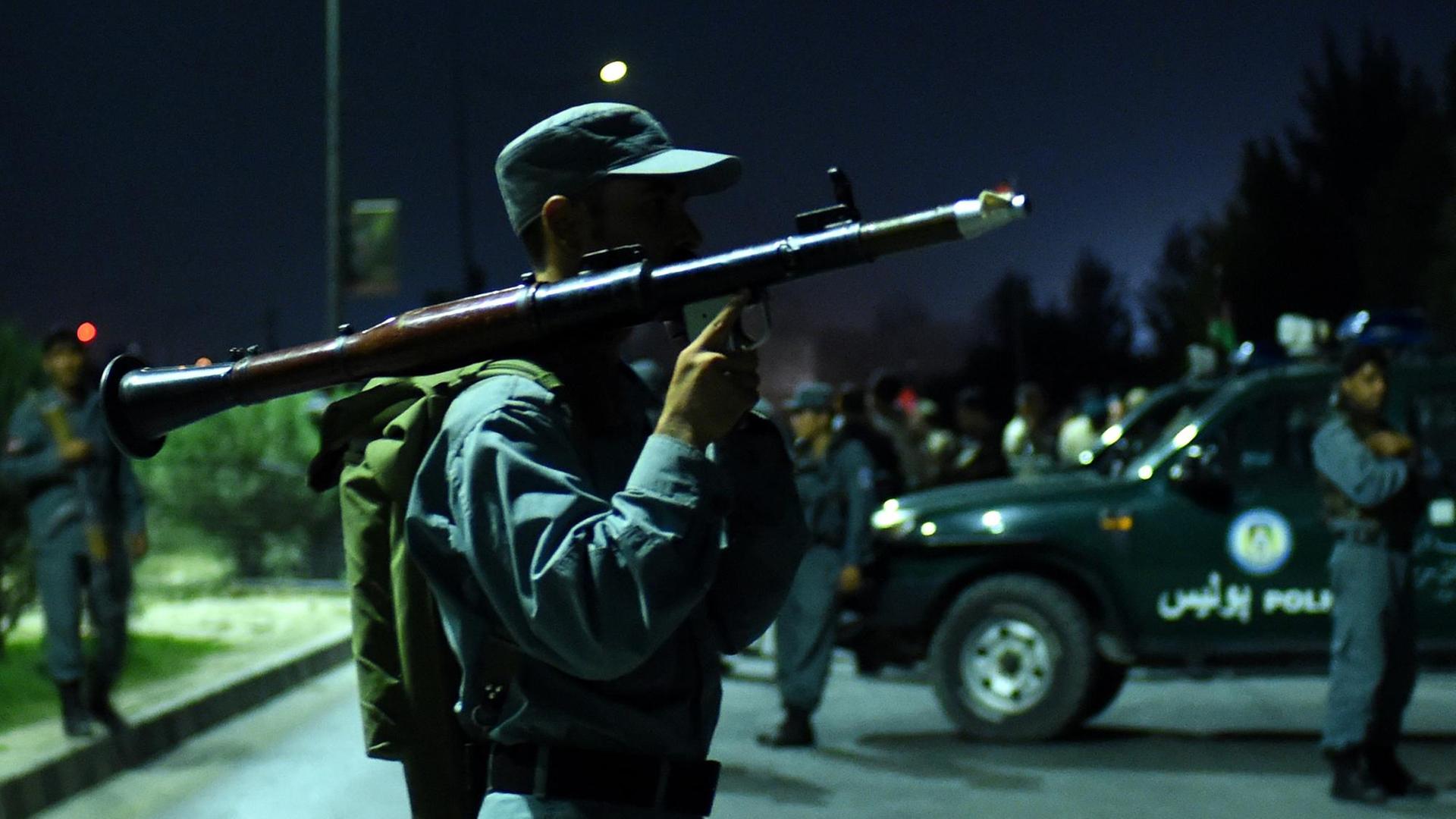 Ein afghanischer Polizist steht mit einer Waffe in der Stadt Kabul vor der Amerikanischen Universität. Ein afghanischer Polizist steht mit einer Waffe in der Stadt Kabul vor der Amerikanischen Universität.