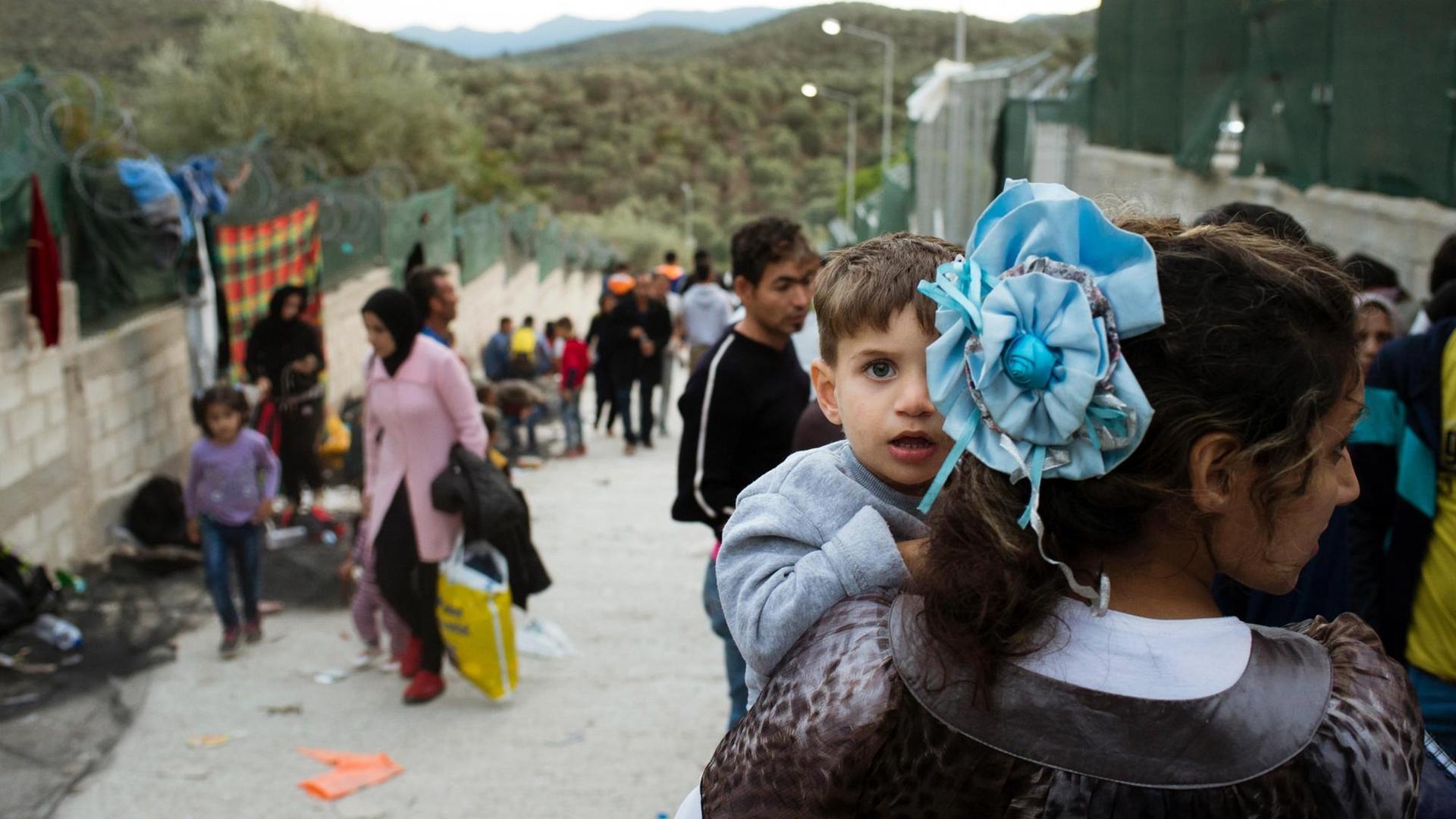 Ein Flüchtlingskind schaut über die Schulter seiner Mutter in einem Flüchtlingslager in Moria auf der griechischen Insel Lesbos.