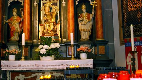 Maialtar in der St. Lambertuskirche in Düsseldorf: Eine Marienstatue mit Jesuskind auf dem Arm, eingerahmt von Kerzen und Blumen