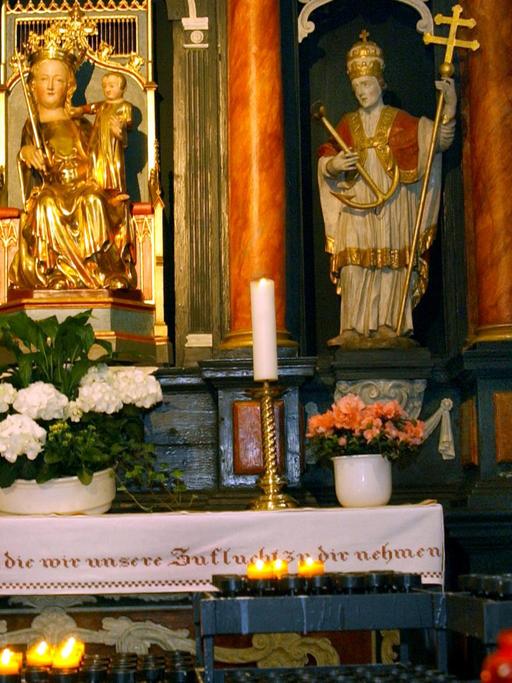 Maialtar in der St. Lambertuskirche in Düsseldorf: Eine Marienstatue mit Jesuskind auf dem Arm, eingerahmt von Kerzen und Blumen
