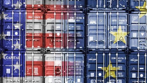 Das Bild zeigt gestapelte Container in den Farben der Flaggen von den USA und der EU.