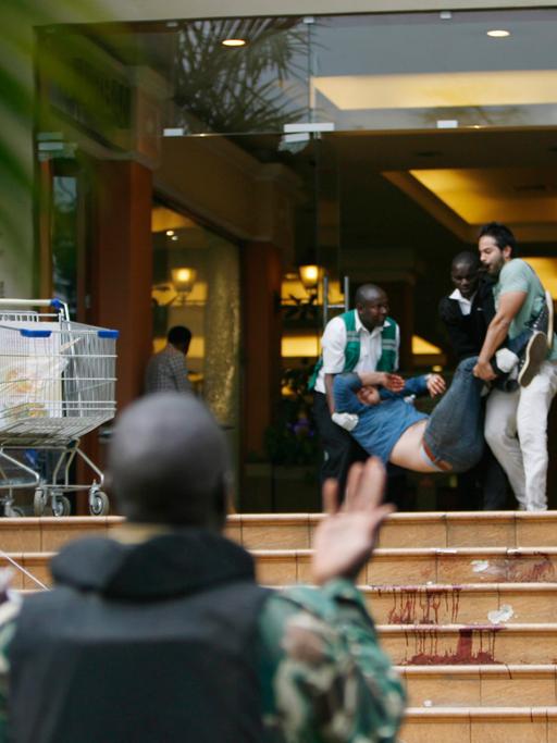 Zwei Leute tragen einen Verwundeten aus der Westgate-Shopping Mall in Kenia, Nairobi, am 21 September 2013.