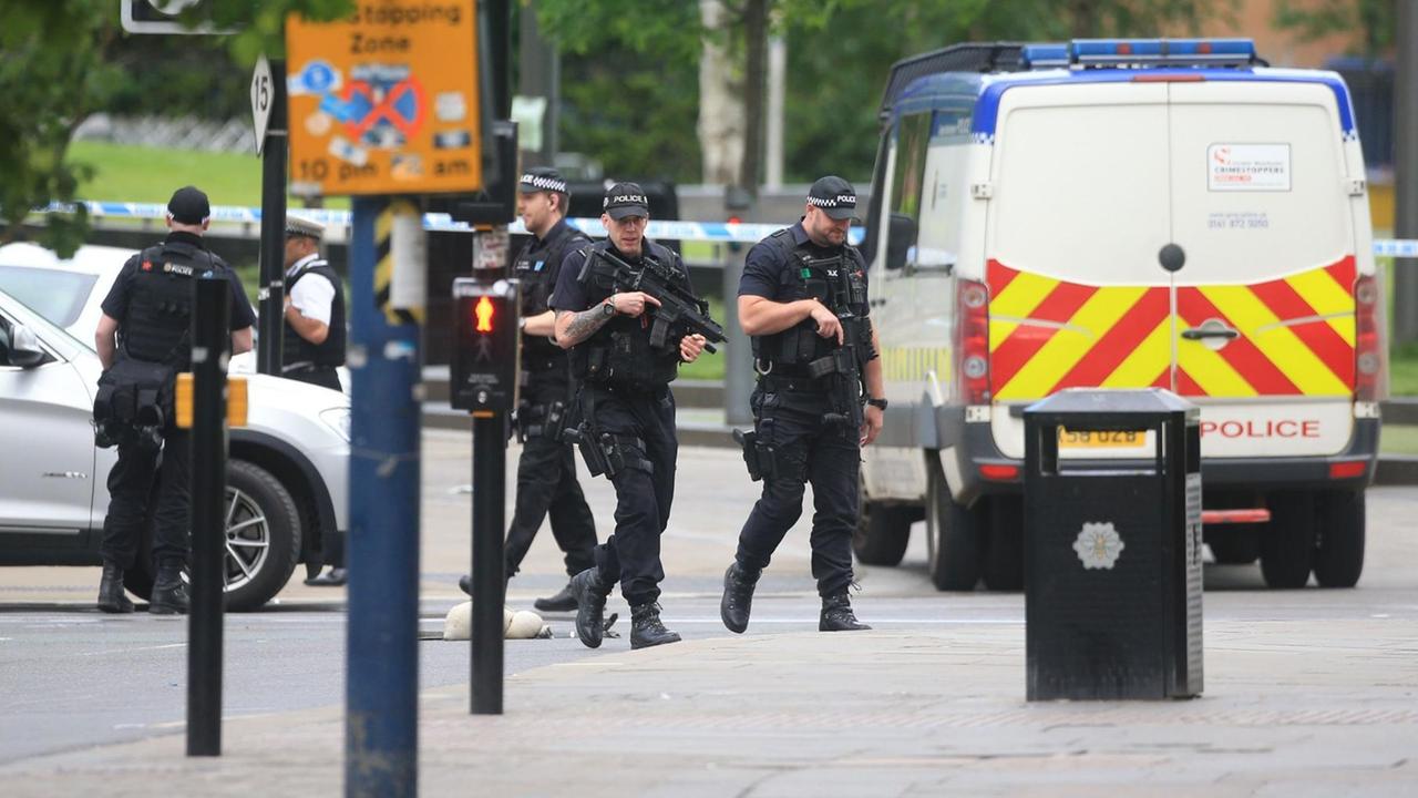 Die Polizisten laufen mit den Waffen im Anschlag über eine Straße, dahinter steht eine Polizeiwanne. Die Polizisten laufen mit den Waffen im Anschlag über eine Straße, dahinter steht eine Polizeiwanne.