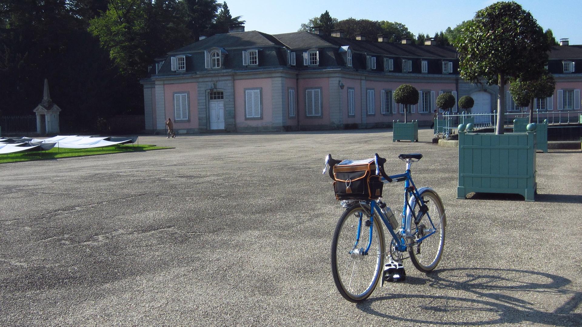 Ein Fahrrad steht an einem sonnigen Tag im Park von Schloss Benrath, Düsseldorf