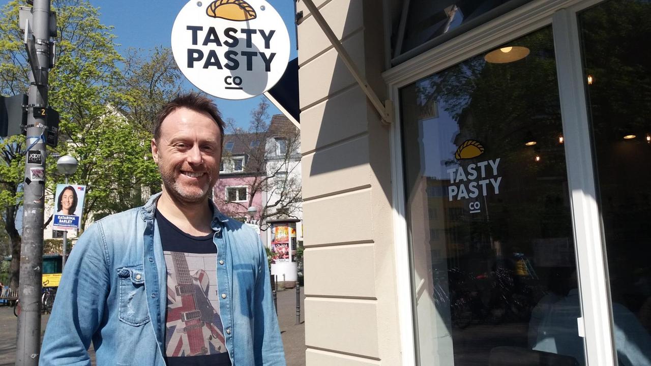 Daniel steht vor seinem Café in Köln