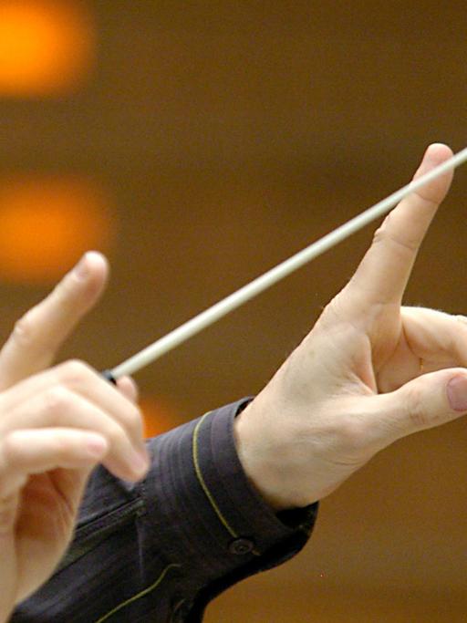 Zwei Hände dirigieren ein Orchester.