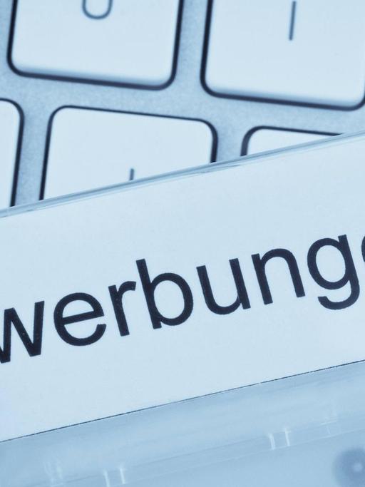 Bewerbungsmappen auf einer Tastatur.