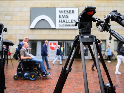 Personen sind während des letzten Prozesstages des Patientenmörders Niels Högel vor der Weser-Ems-Halle hinter zwei Filmstativen.