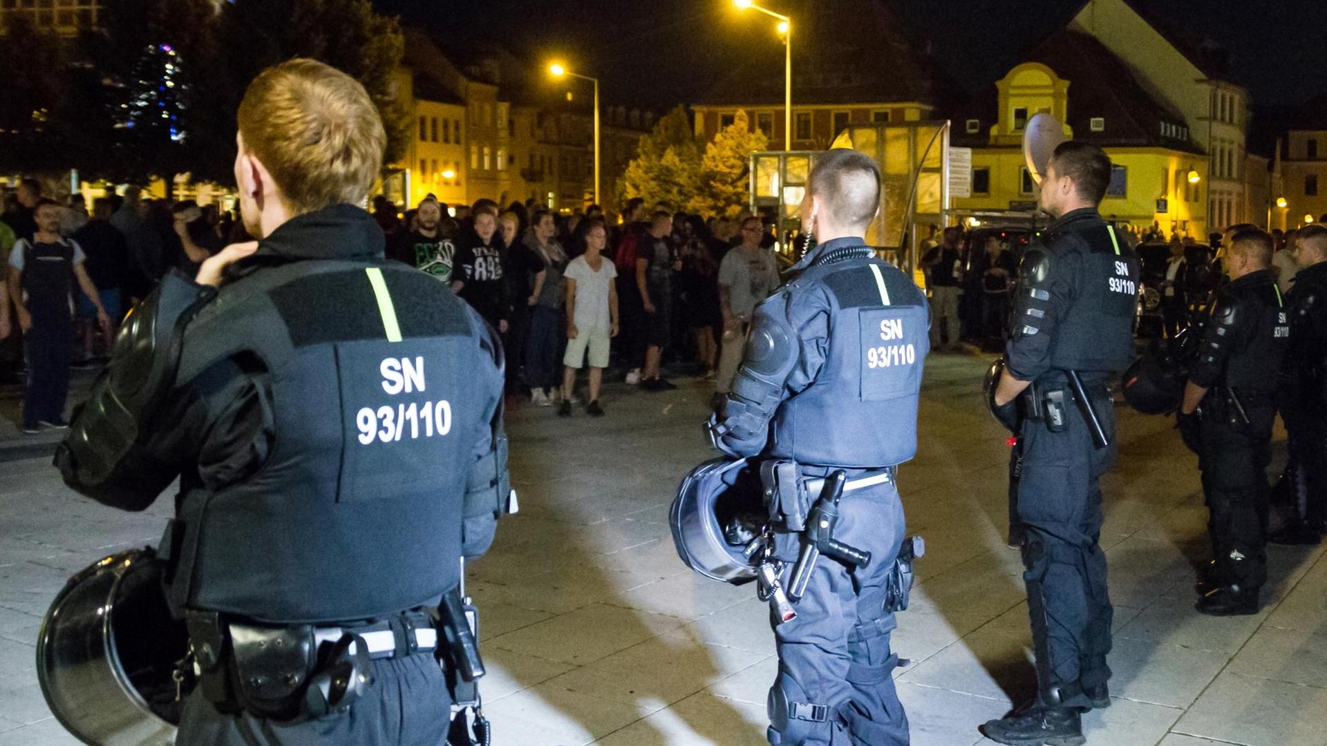 Bewaffnete Polizeibeamte stehen in Bautzen (Sachsen) auf dem Kornmarkt etwa 350 Versammlungsteilnehmern aus dem politisch rechten Spektrum gegenüber. Es ist dunkel.