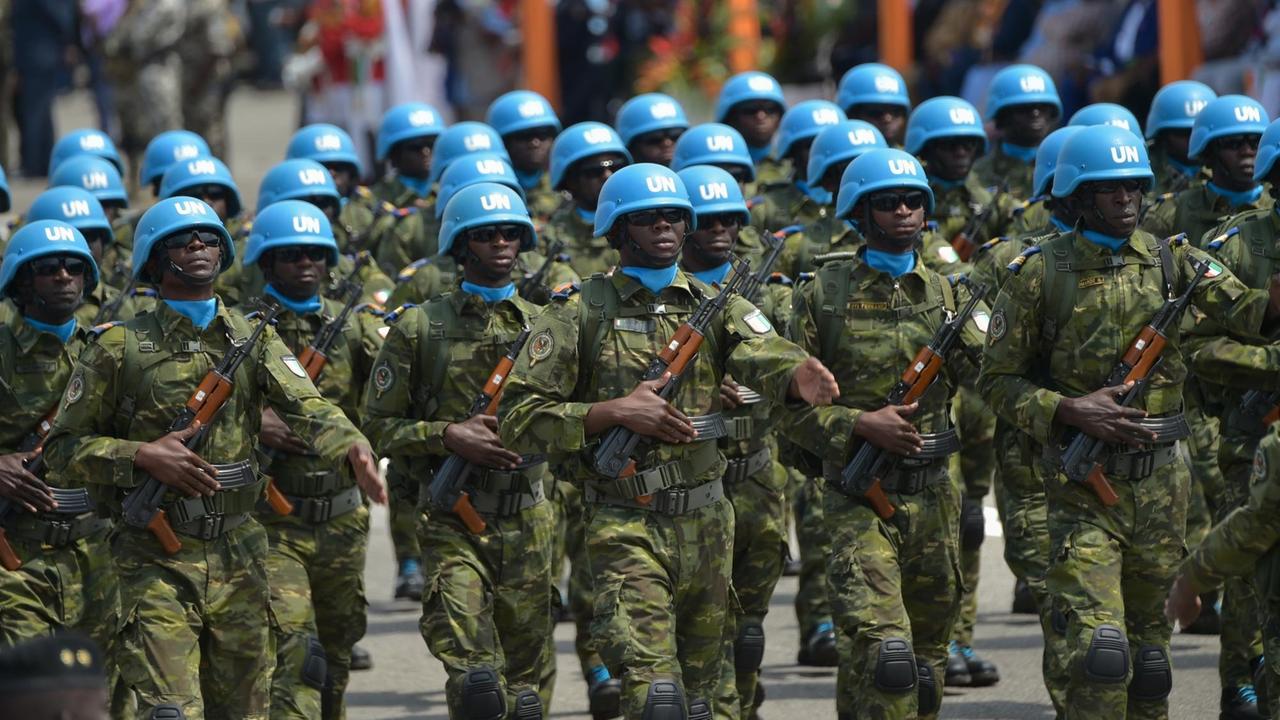Blauhelm-Soldaten der UN-Mission "Minusma" bei einer Militärparade. Sie tragen blaue Helme und Gewehre.