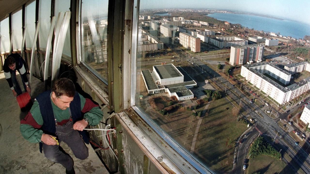 Techniker verlegten 1997 im auch damals geschlossenen Turmcafe des Schweriner Fernsehturms Kabel. Durch die Fenster sieht man Plattenbautender Stadt.