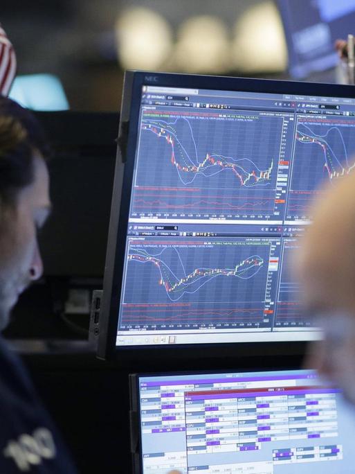 Händler stehen am 02.03.2020 an der Wall auf dem Parkett der Wall Street in New York und blicken auf die Aktienkurse auf den Bildschirmen.