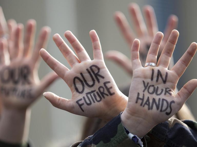 Protestmarsch von Jugendlichen in Brüssel, Belgien. Auf den hochgehaltenen Handflächen steht: "Our Future - in your Hands".