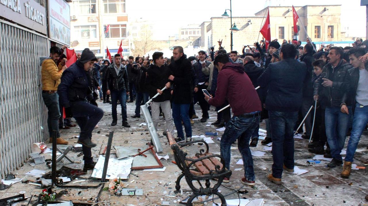 Eine Menschenmenge vor dem HDP-Gebäude, auf dem Boden liegen Papiere und andere Gegenstände, einzelne Personen treten darauf herum. 