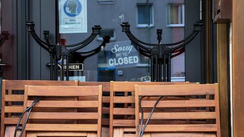 Zusammengeklappte Stühle und Tische vor einem Berliner Restaurant. Schild mit Schriftzug: Sorry, we are closed.