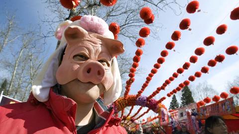 Ein Chinese trägt eine Schweinsmaske