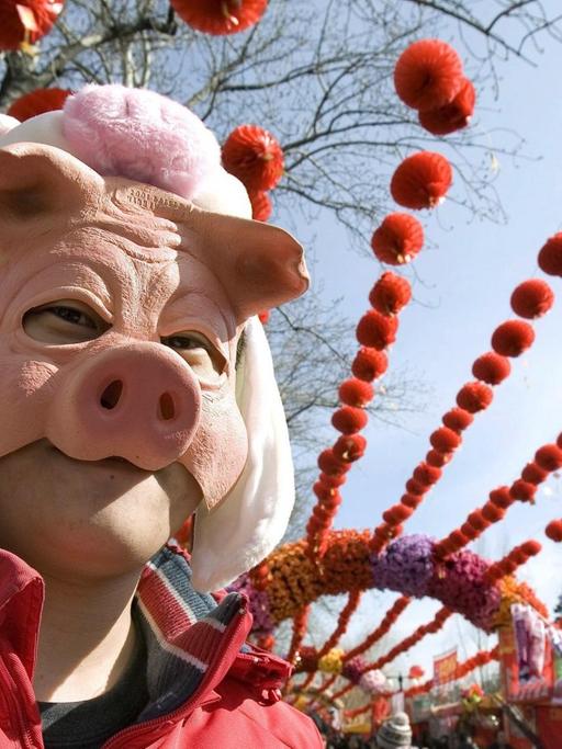 Ein Chinese trägt eine Schweinsmaske
