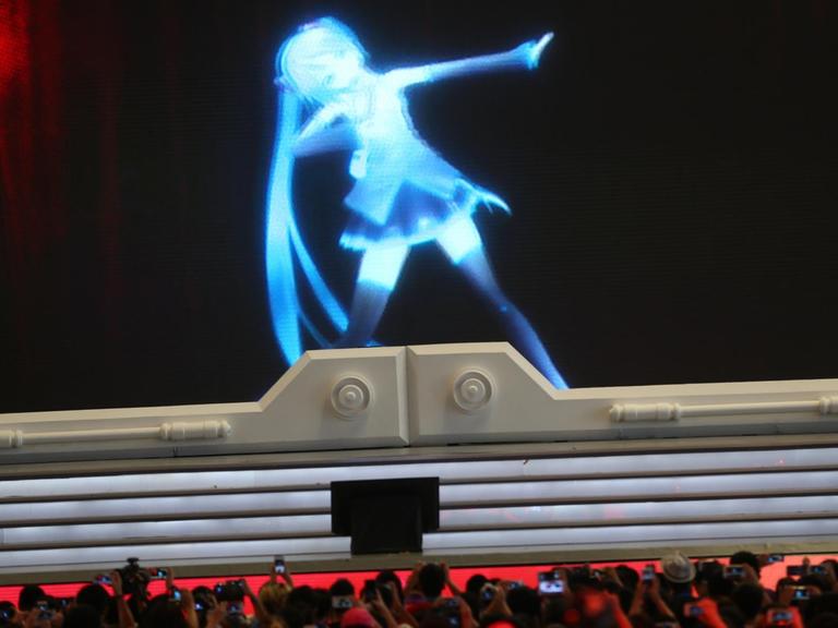 Eine Performance mit der digitalen Figur Hatsune Miku, vorne Zuschauer.