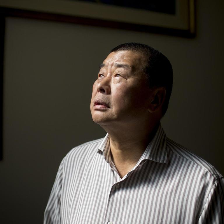 Jimmy Lai steht vor einer dunklen Wand und schaut ins Licht