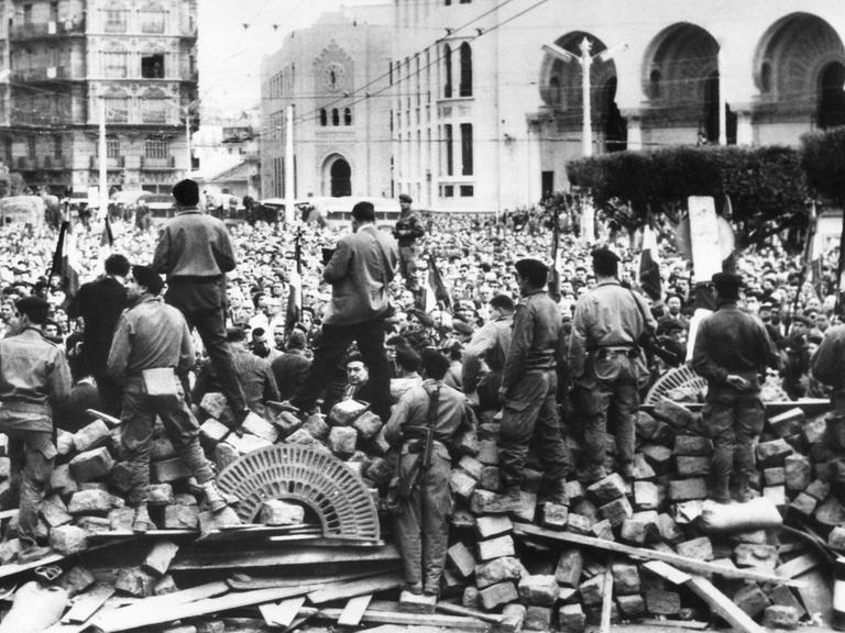 Im Hintergrund Algerien-Franzosen, Gegner der Unabhängigkeit Algeriens, während einer Demonstration Ende Januar 1960 in Algier. Im Vordergrund an den Barrikaden französische Fallschirmspringer.
