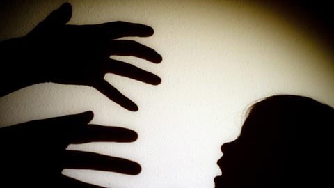 Das Schattenbild von zwei Händen die ein Kind greifen wollen. 
