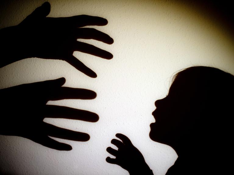 Das Schattenbild von zwei Händen die ein Kind greifen wollen. 