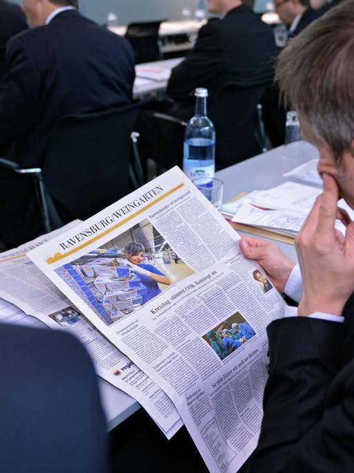Die "Schwäbische Zeitung" wird bei einer Geschäftstagung von einem Mann im Anzug gelesen.