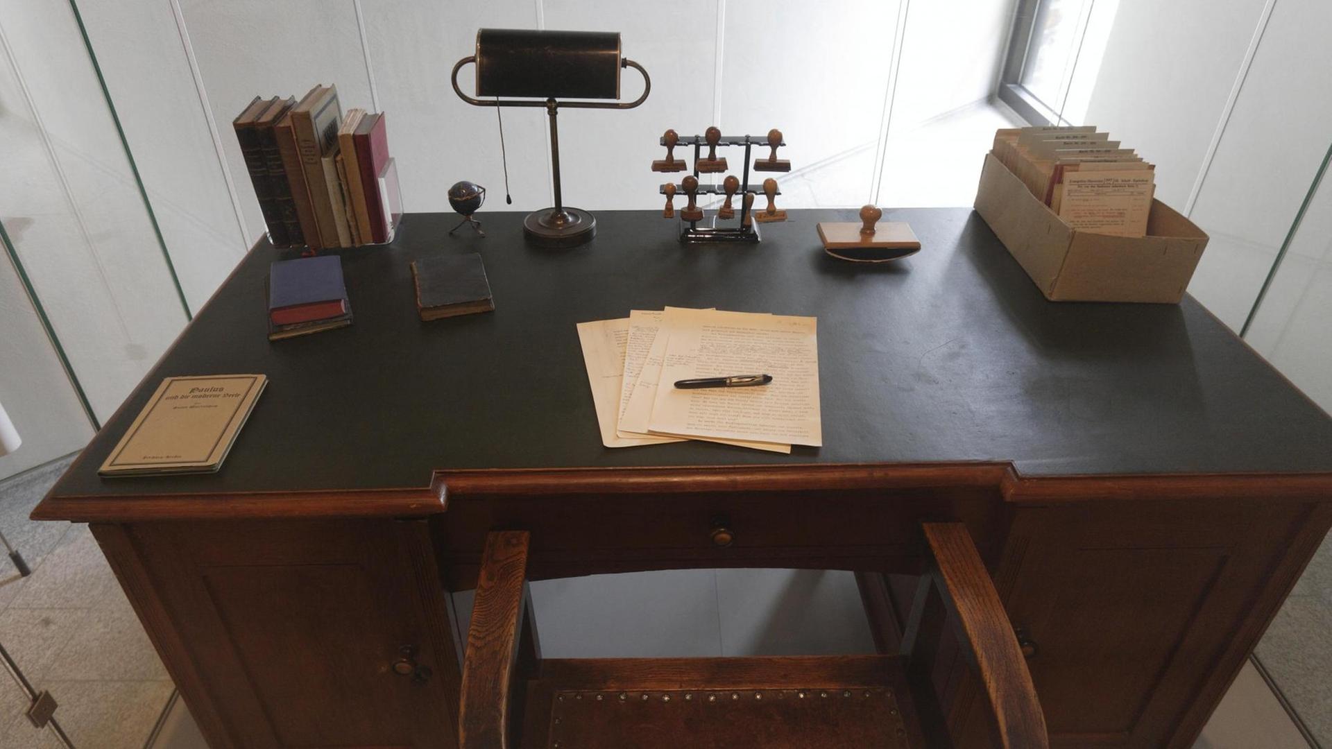 Ein alter Schreibtisch mit Büromaterial: Stiften, Papier, Zettelkasten.