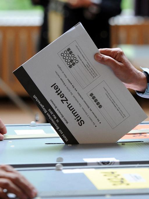 Eine Wählerin steckt ihre Stimme zur Bürgerschaftswahl in Bremen in die Wahlurne.